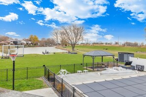 Un cortile recintato con canestro da basket, un gazebo e un patio arredato per esterni.