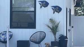 Um edifício com fachada branca, uma janela grande e dois peixes decorativos fixados na parede.