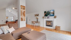 Uma sala de estar com lareira, um sofá, uma mesa de centro e um espaço de jantar com uma cadeira e uma mesa.