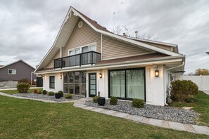 Een tweelaags huis met een balkon, grote ramen en een verzorgd gazon.