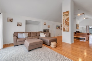 A spacious living room with a sectional sofa, ottoman, and a round rug. - Grand River Retreat: Pool, Hot Tub & Dock (Belle River)
