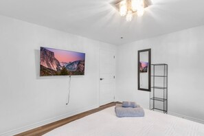 A bedroom with a bed, a TV mounted on the wall, a door, and a mirror. - Grand River Retreat: Pool, Hot Tub & Dock (Belle River)