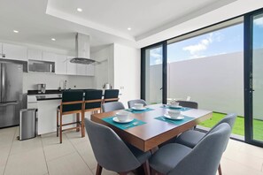 Eine moderne Küche mit weißen Schränken, einem Edelstahl-Kühlschrank und einem Essbereich mit Tisch für vier Personen.