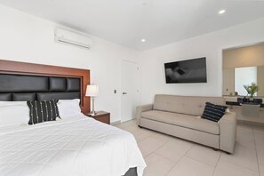 Ein Hotelzimmer mit Bett, Sofa, Fernseher, Spiegel und Bad.
