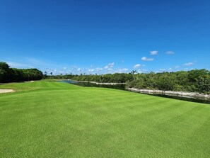A golf course with a clear sky, a water body, and dense greenery. - 2bd Tulum Country Club/PGA golf/Mid term/grocery (Tulum)
