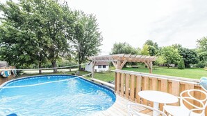 Un pati amb piscina, terrassa de fusta i moble d'exterior.