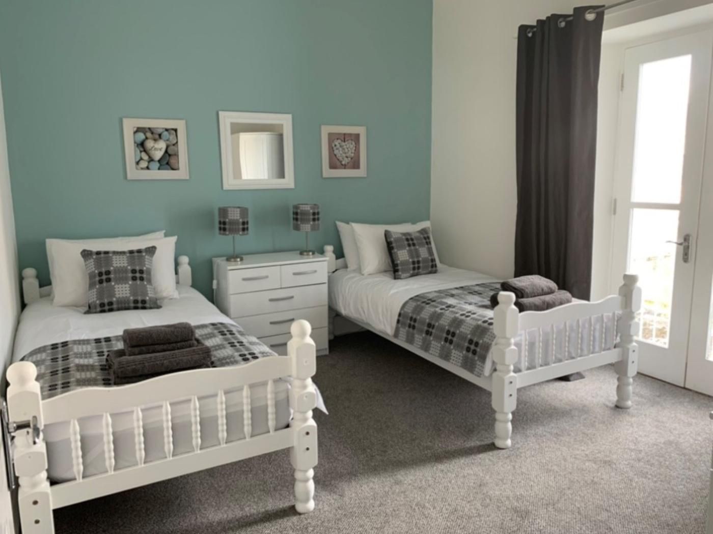 A bedroom with two beds, a dresser, and a mirror.