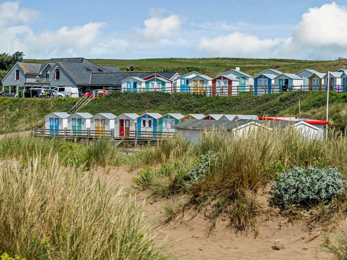 Une rangée de cabanes de plage, avec un grand bâtiment en arrière-plan.