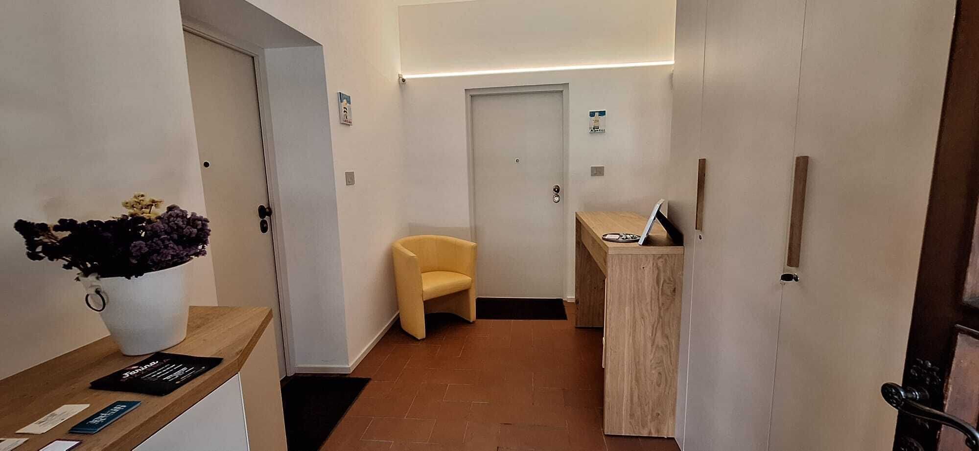 Un espace d’accueil d’hôtel comprenant un comptoir de réception, une chaise et une porte.