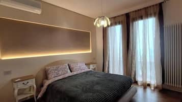 Un dormitorio moderno con una cama grande, mesitas de noche, una lámpara de pared y una ventana con cortinas.
