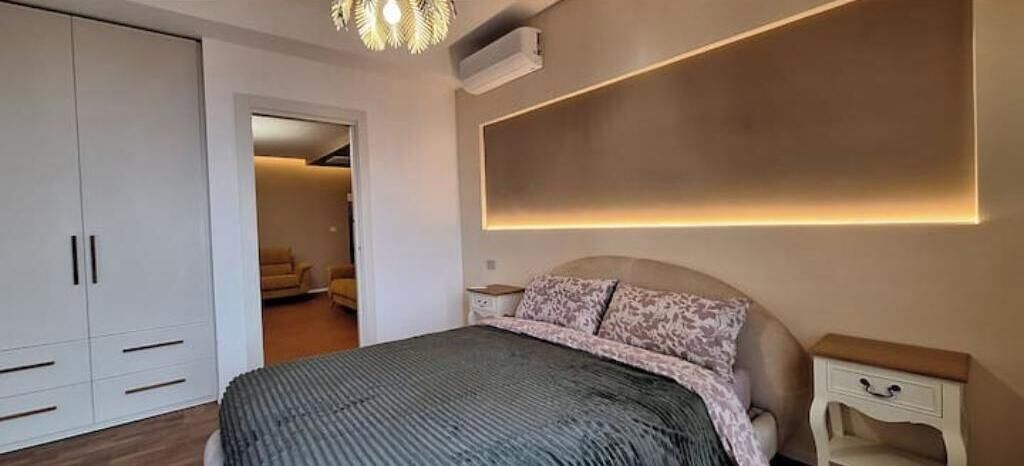 A bedroom with a bed, bedside tables, a wardrobe, and a ceiling light fixture.