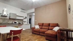 A modern living room with a sofa, a dining table with chairs, and a kitchen area with cabinets and a microwave. - Corina's Place Bologna Villa (Bologna)