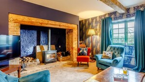 Ein gemütliches Wohnzimmer mit Kamin, Fernseher und bequemen Sitzgelegenheiten.