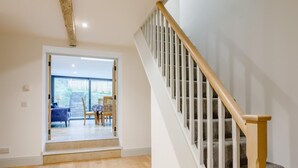 Eine Treppe mit hölzernen Geländern und Teppichstufen, die zu einem Raum mit Blick durch eine Glastür führt.
