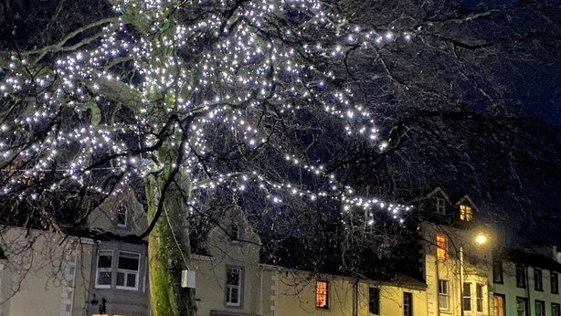 A tree with string lights, a row of houses, and a street. - 2 Bed in Keswick (oc-80515) (Keswick)