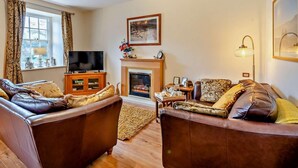 A living room with two leather sofas, a fireplace, a television, and a framed picture on the wall. - 2 Bed in Keswick (oc-80515) (Keswick)