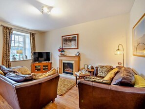 A living room with two leather sofas, a fireplace, a television, and a framed picture on the wall. - 2 Bed in Keswick (oc-80515) (Keswick)