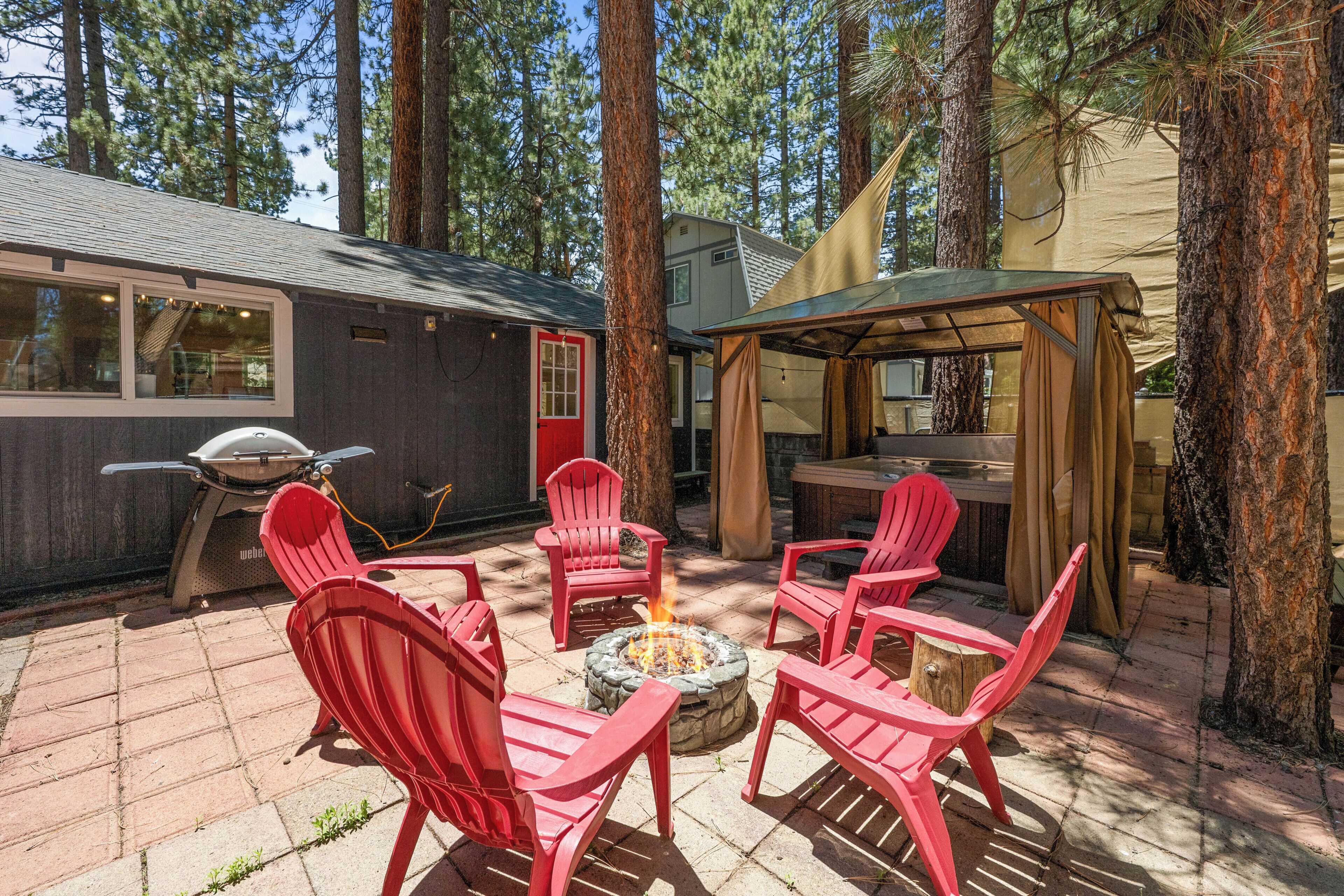 Ein Patio mit roten Adirondack-Stühlen, einer Feuerstelle aus Stein und einem überdachten Sitzbereich.