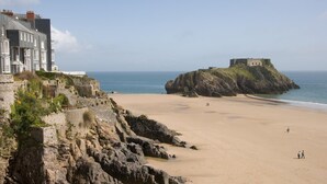 A coastal beach with a historic building and a fort on a rocky outcrop. - 1 Bed in Tenby (oc-fb024) (Tenby)