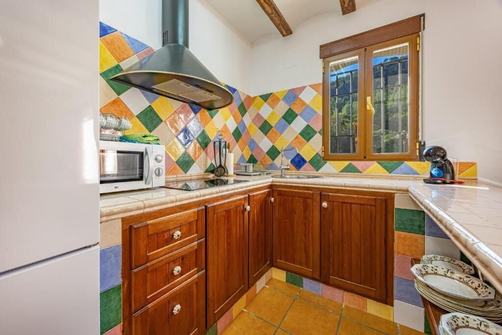 Una cocina con armarios de madera, microondas, estufa y ventana con vistas.