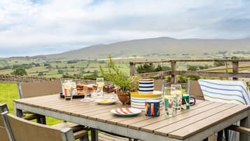 A wooden table set outdoors with a scenic view of rolling hills in the background.