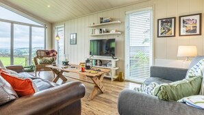 A spacious living room with a large TV, comfortable seating, and a view of the countryside. - 2 Bed in Wigton (oc-80563) (Caldbeck)