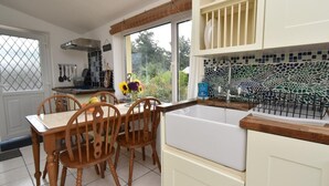 Una cocina con mesa, sillas, ventana y salpicadero de azulejos.