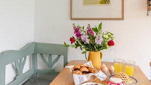 Ett matbord med en vas med blommor, en korg med croissanter, ägg, våfflor och glas med apelsinjuice.