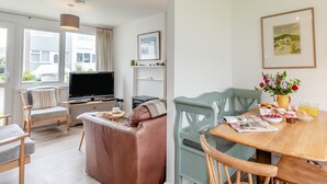Ett modernt vardagsrum med TV, soffa och en matplats med stolar och ett bord.