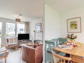 A modern living room with a TV, sofa, and dining area with chairs and a table. - 2 Bed in Pembroke (oc-fb101) (Freshwater East)