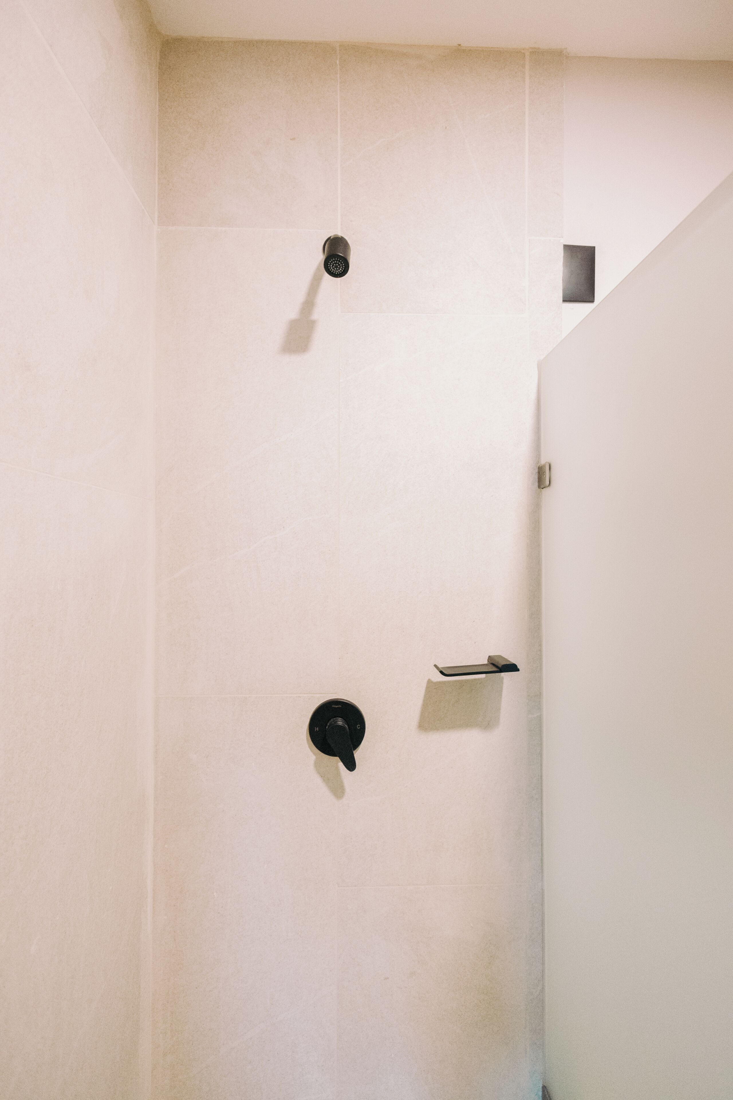 A shower with a handheld showerhead and a towel rack.