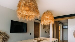 Uma cozinha moderna com ilha central, luminárias pendentes e uma TV de tela plana na parede.