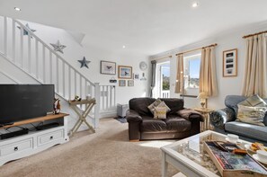 A living room with a TV, leather sofa, and a coffee table with snacks. - 3 Bed in Freshwater East (oc-fb100) (Freshwater East)