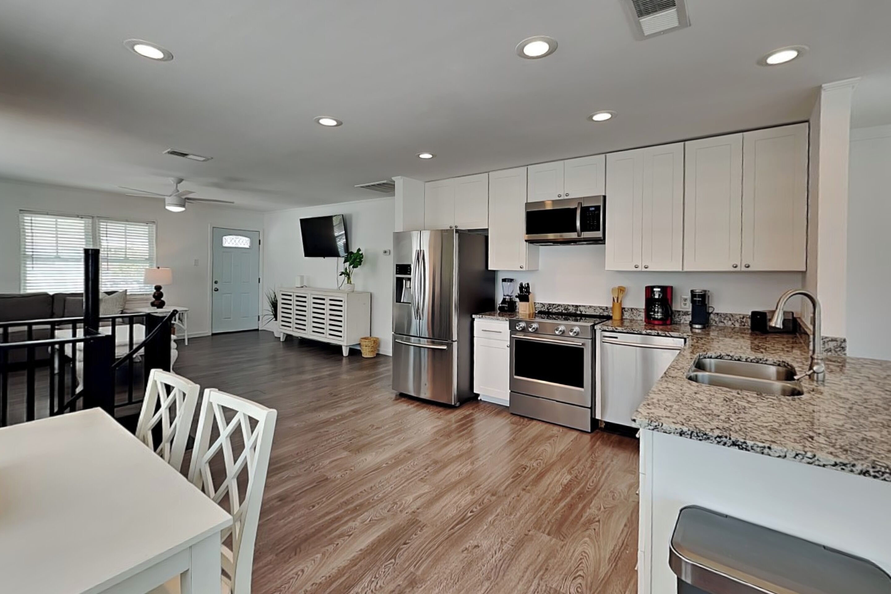 A modern kitchen with white cabinets, stainless steel appliances, and a granite countertop.