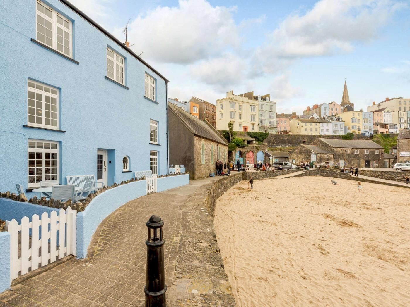 A coastal town with a prominent blue building, a sandy beach, and historic architecture.