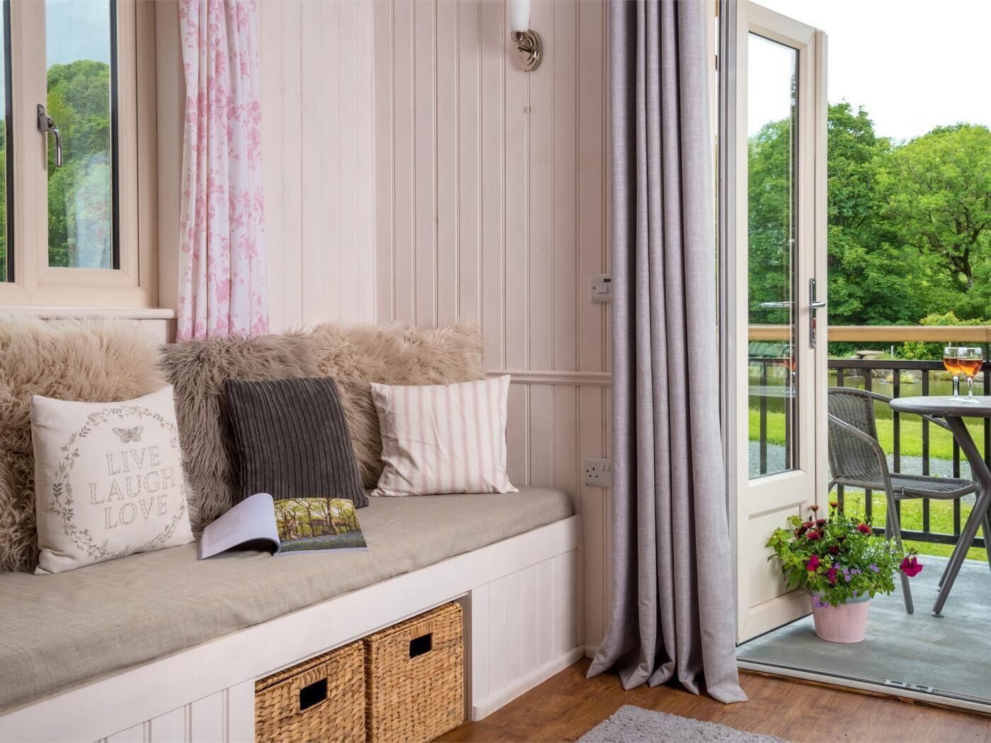A cozy seating area with a cushioned bench, storage baskets, and a view of greenery outside.