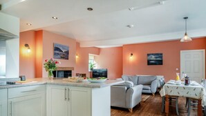 Una cocina moderna con una isla central, una zona de comedor con mesa y sillas, y un espacio de sala con sofá.