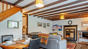 Ein gemütliches Wohnzimmer mit Kamin, einem Essbereich mit Holztisch und Stühlen sowie einem grauen Sofa.