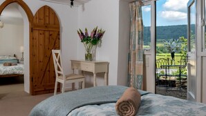 A bedroom with a bed, a desk, a chair, and a view of a green landscape through a window. - 2 Bed in Brecon (oc-bn102) (Talybont-on-Usk)