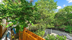 Une terrasse en bois surplombant un cours d’eau bordé d’une végétation luxuriante et délimitée par une clôture en bois.