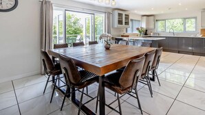 Una cocina moderna con comedor, ventanas amplias y un reloj en la pared.