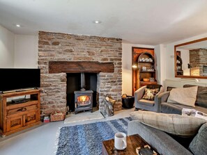 A cozy living room with a stone fireplace, a flat-screen TV, a grey sofa, and a coffee table. - 2 Bed in Crickhowell (oc-bn194) (Cwmdu)