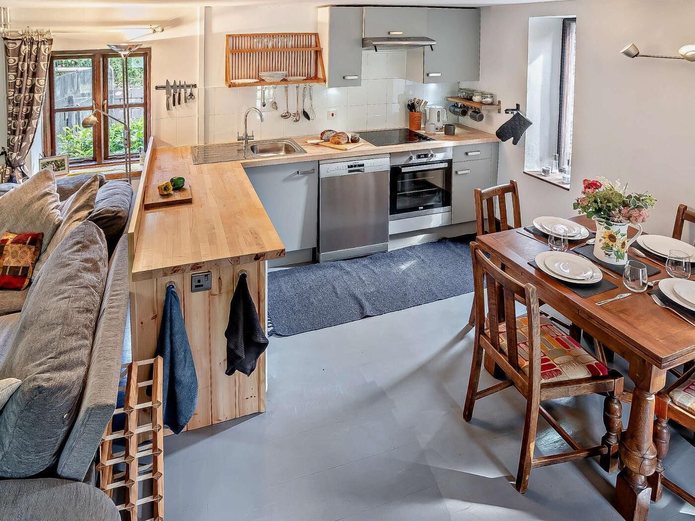 Una cucina compatta con zona pranzo, forno a incasso e finestra vista sul verde.
