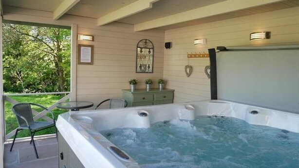 Un jacuzzi con vistas al exterior, una pequeña mesa y sillas en una terraza.