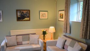 Ein Wohnzimmer mit zwei Sofas, einem Tisch mit Lampe und gerahmten Bildern an der Wand.