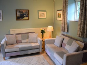 Ein Wohnzimmer mit zwei Sofas, einem Tisch mit Lampe und gerahmten Bildern an der Wand.