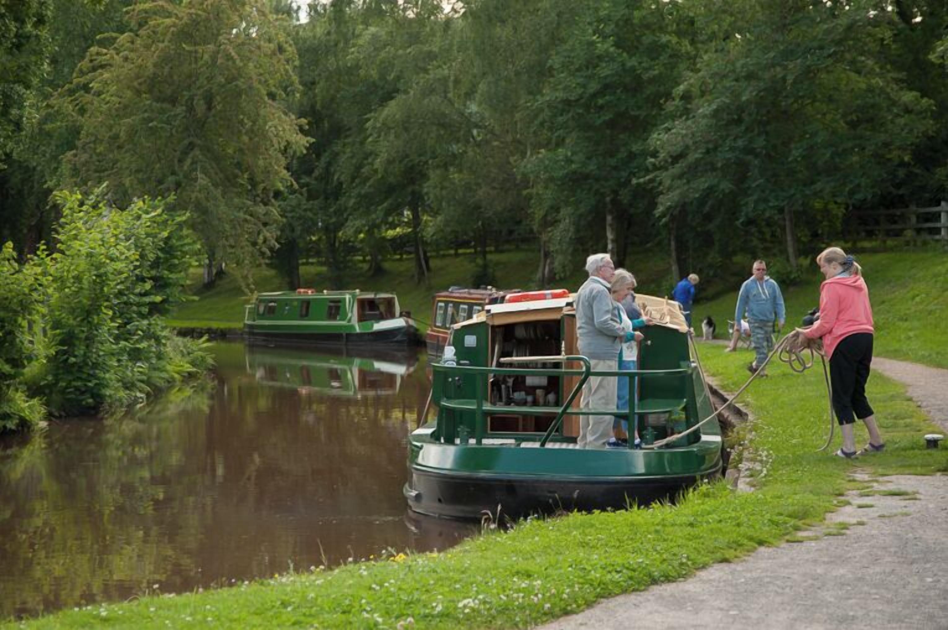 A narrow waterway with boats docked, surrounded by greenery.