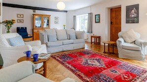 Una sala de estar con un sofá a rayas, un tapete rojo estampado, un mueble de madera y una silla azul.
