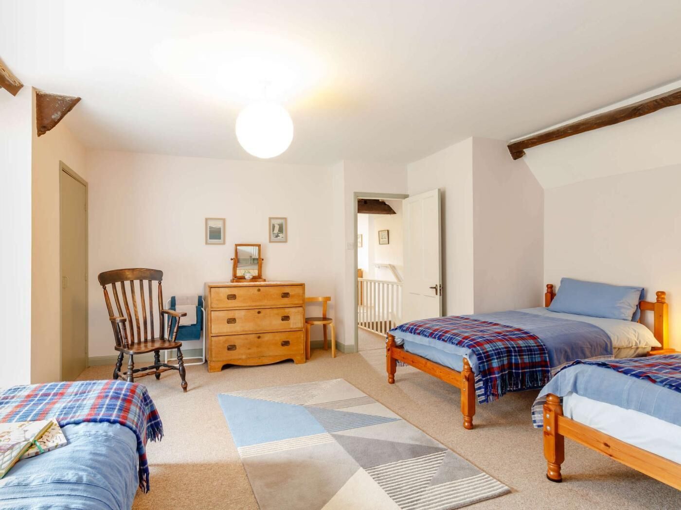 Une chambre avec deux lits, une commode, une chaise et un tapis.