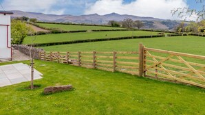 Paisaje rural con una verja de madera, un muro de piedra y un campo cubierto de hierba.